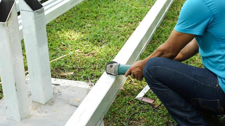 Worker repairing metal components for gutter maintenance in a backyard to ensure proper drainage and prevent home damage.