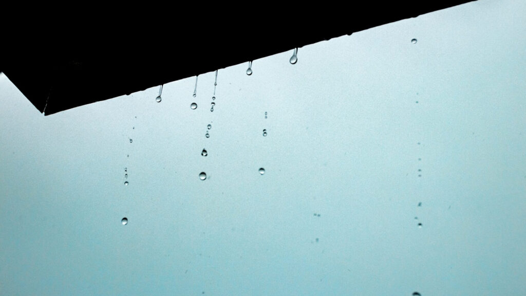 Rainwater dripping from clogged gutters in Miami, indicating the need for rain gutters repair to prevent water damage.